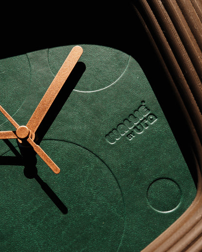 Green wallie clock with brown hands and 'Wallie by URA' branding on a dark background