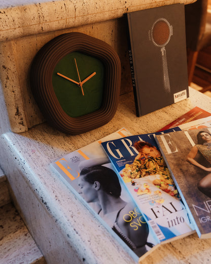 Wallie Clock on a ledge with magazines underneath. Made by Ura Watches / EON TIME