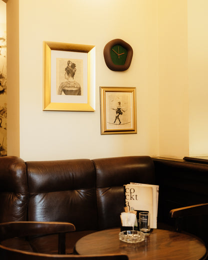 Cozy interior with a brown leather sofa, framed pictures, and a Wallie clock on a wall. Made by Ura Watches / EON TIME