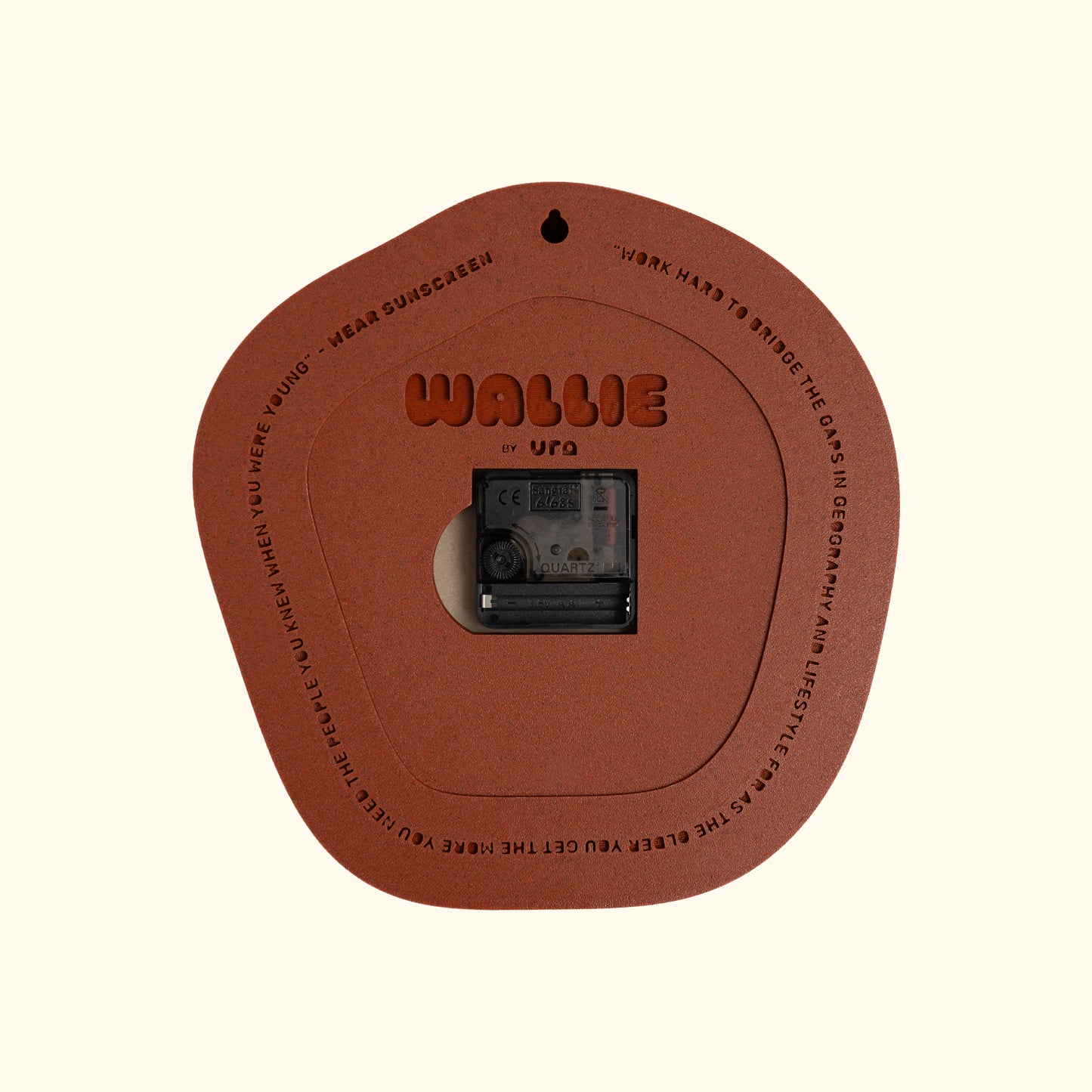 A terracotta brown circular  WALLIE clock branded 'WALLIE by URA'. The product is displayed on a solid cream background. Made by Ura Watches / EON TIME