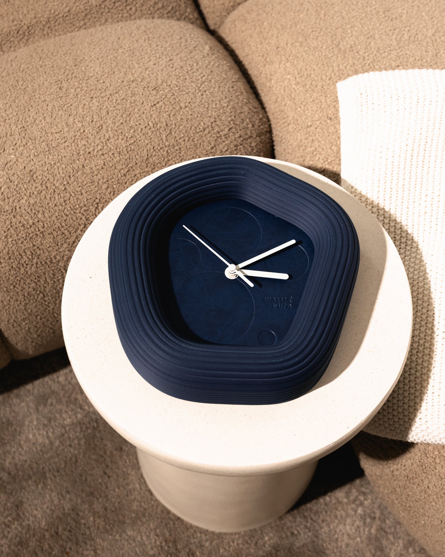 Blue Wallie wall clock with white casing on a beige surface made by Ura Watces in Croatia