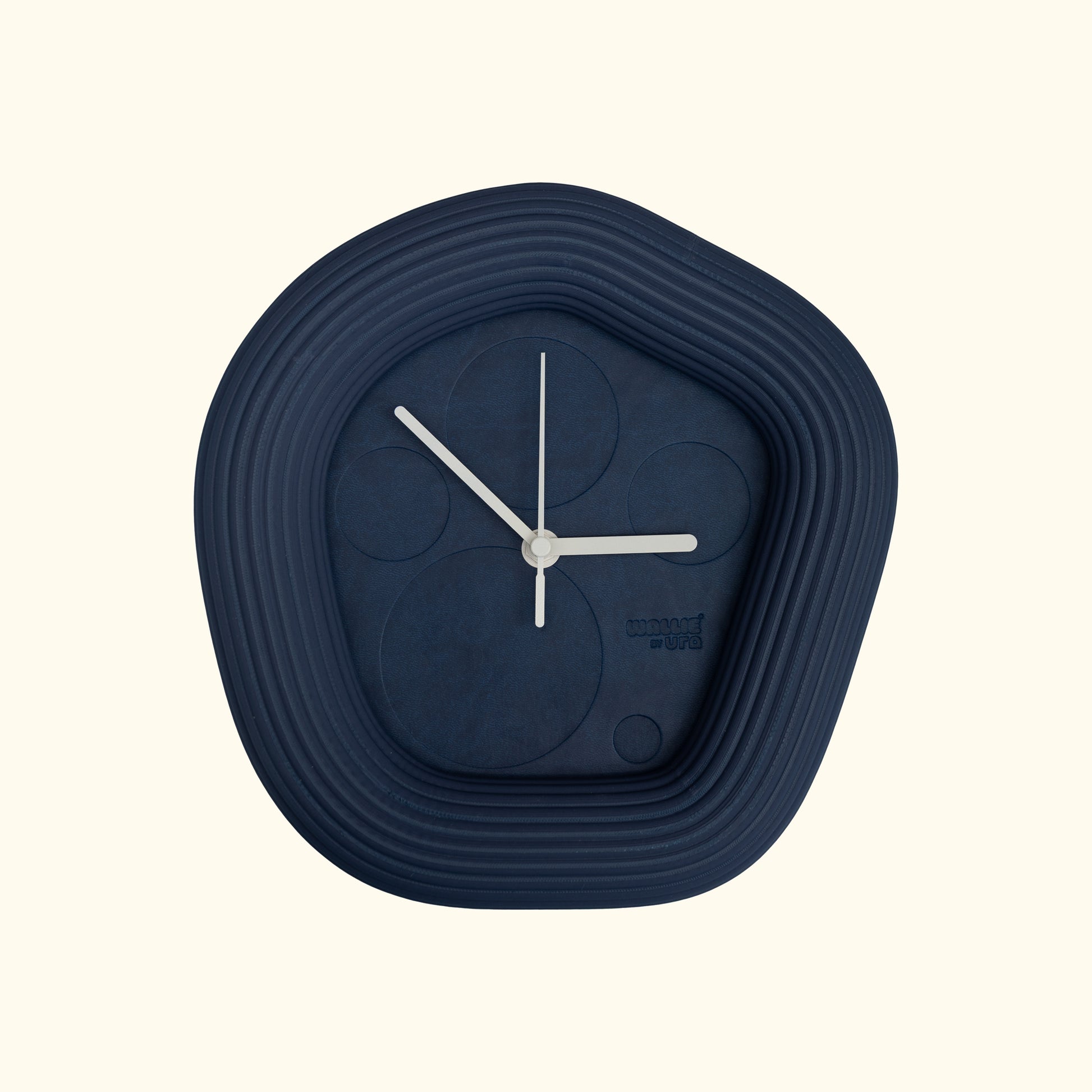 Blue wall clock with white hands on a off white background