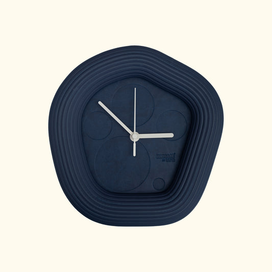 Blue wall clock with white hands on a off white background