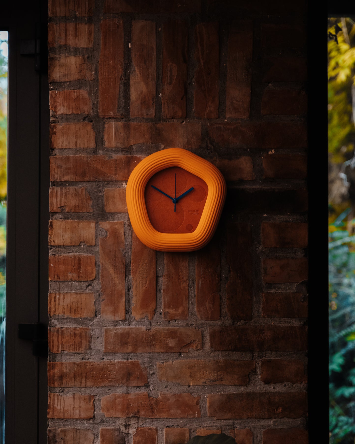 Orange Wallie wall clock on a brick wall