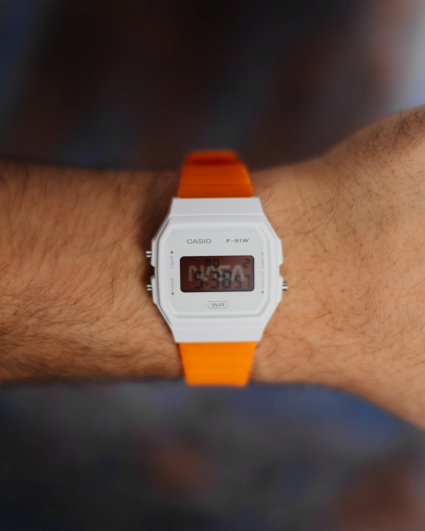 NASA F-91 modified Casio digital watch with white case and orange strap on wrist
