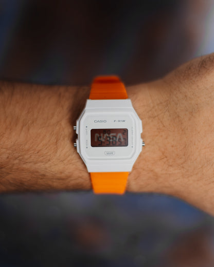 NASA F-91 modified Casio digital watch with white case and orange strap on wrist